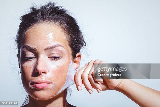 beauty portrait of a young woman applying-removing face mask - chipping stock pictures, royalty-free photos & images