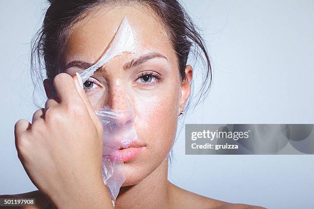 ritratto di bellezza di una giovane donna applica-togliere maschera viso - esfoliazione foto e immagini stock