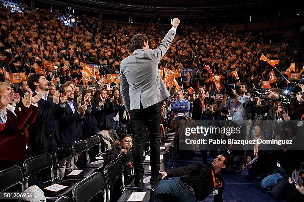 Albert Rivera , leader of Ciudadanos stands on a chair as he rises his fist while a man sit on the ground to hold his chair during a campaign rally...