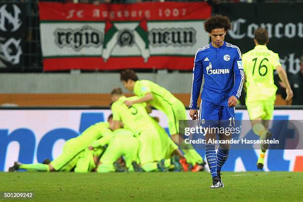 Leroy Sane of Schalke looks dejected whilst players of Augsburg celebrate the winning goal during the Bundesliga match between FC Augsburg and FC...