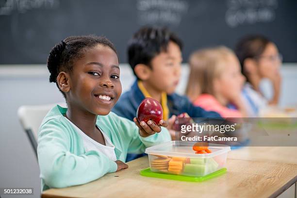 little girl eating an apple in class - child eating a fruit stockfoto's en -beelden