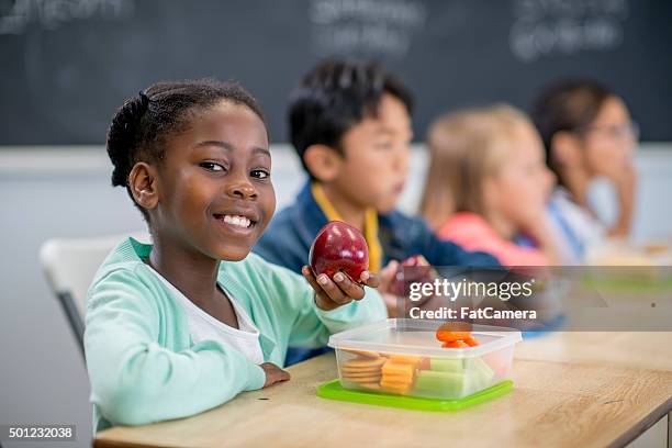 little girl eating an apple in class - kid school lunch stock pictures, royalty-free photos & images