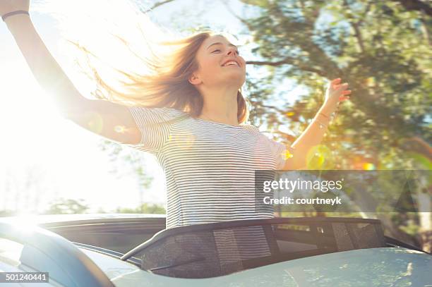 fröhliche frau schiefen sie ein auto sonnendach - tousled hair stock-fotos und bilder