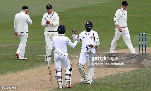 Dinesh Chandimal of Sri Lanka is congratulated by his captain Angelo Mathews on scoring 50 runs during day five of the First Test match between New...