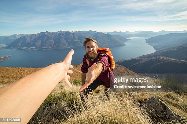 giovane uomo mostra mano da hiking per ottenere assistenza - reaching foto e immagini stock