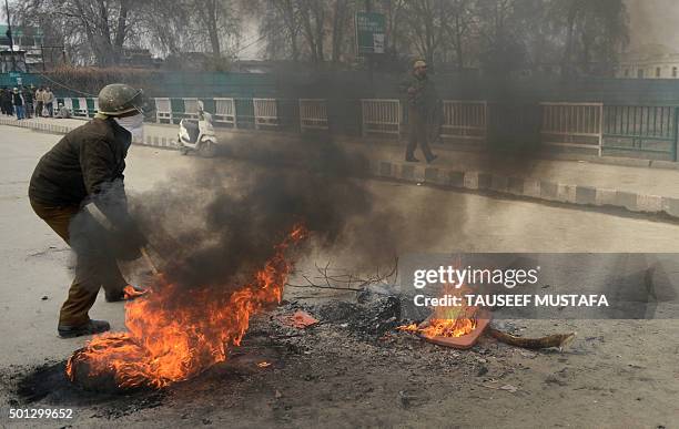 Indian police remove burning tyres during a protest in Srinagar on December 14, 2015. Kashmiri protestors rallied against a new food safety act to be...