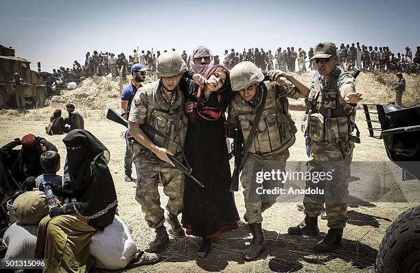 Turkish soldiers help a Syrian woman to cross into Turkey from the borderline in Akcakale district of Sanliurfa on June 10, 2015.