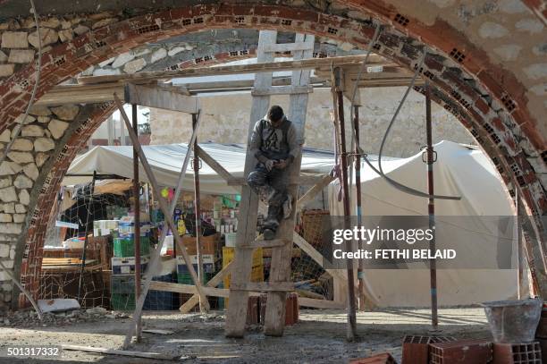 Tunisian worker checks his phone during a break at the construction site of a new marketplace on December 14 in the impoverished central town of Sidi...