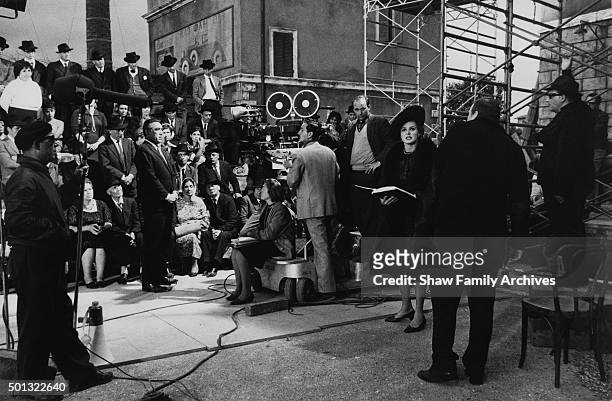 Ingrid Bergman and Anthony Quinn and a crowd of onlookers with the crew and director Bernhard Wicki in 1963 during the filming of "The Visit" in...