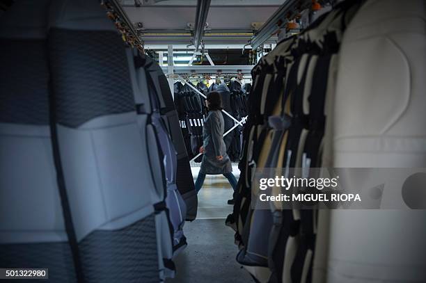 Copo Galicia employee walks past hanging car seats stored at a production line in Mos, northwestern Spain on December 9, 2015. Amid the Spanish...