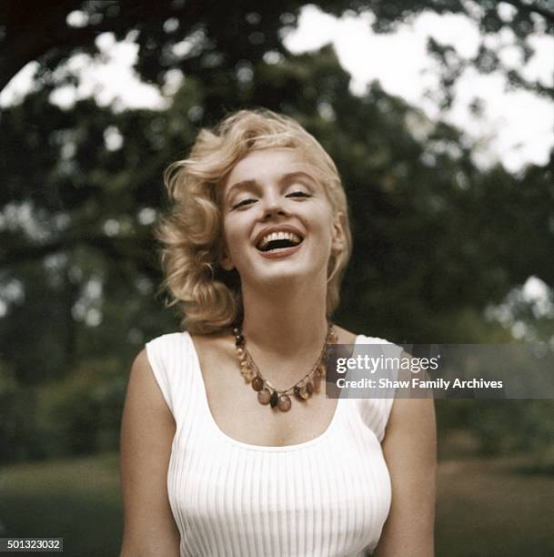 Marilyn Monroe laughs as she poses whilst wearing an amber bead necklace in 1957 in Amagansett, New York.