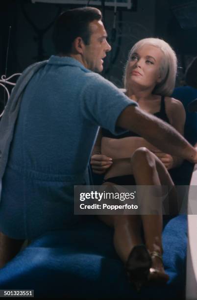 Scottish actor Sean Connery as 'James Bond' pictured with English actress Shirley Eaton playing 'Jill Masterson' in a scene from the film...