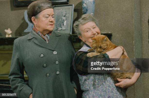 British actresses Violet Carson as 'Ena Sharples' and Margot Bryant as 'Minnie Caldwell' holding a cat pictured together in a scene from the...