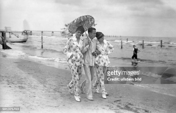 German Empire Kingdom Prussia Pomerania province, Usedom, Heringsdorf: Man and two women walking along the beach - 1918 - Photographer: Haeckel