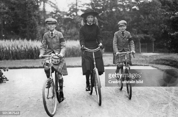 George VI. King of the United Kingdom of Great Britain the later king as a child with his siblings Princess Mary and Prince Henry, cycling in a park...