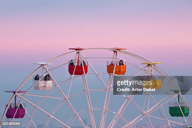 colorful ferris wheel in the tibidabo amusement park mountain with the barcelona city view and the pink sunset sky. - sunset freinds city fotografías e imágenes de stock