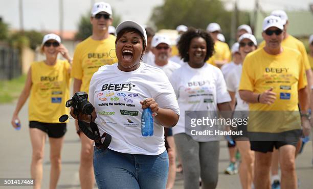 In this handout image provided by Philip Brown, A lady from the Kliptown Youth Program runs ahead of Sir Ian Botham and his supporters as they...