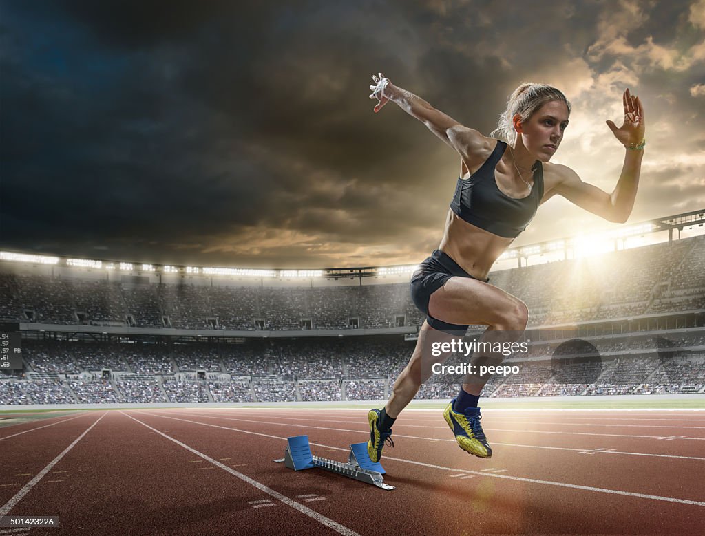 Woman Sprinter in Mid Action Bursting From Blocks During Race