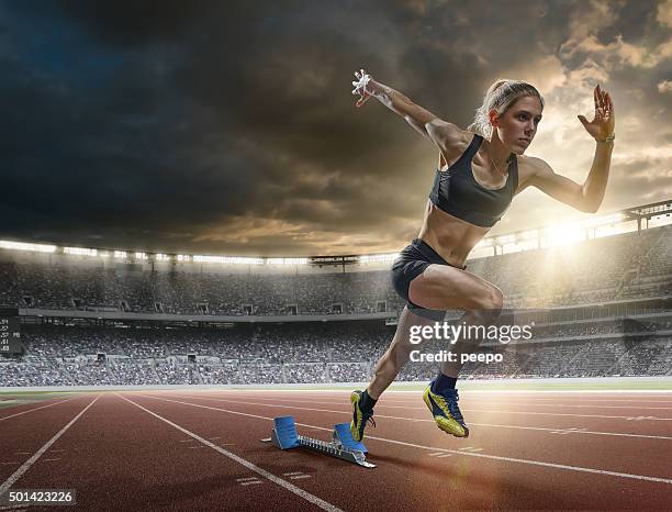 woman sprinter in mid action bursting from blocks during race - running race stock pictures, royalty-free photos & images