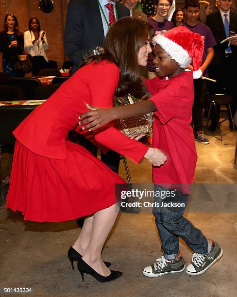 Catherine, Duchess of Cambridge hugs a young boy in a santa hat as she attends the Anna Freud Centre Family School Christmas Party at Anna Freud...