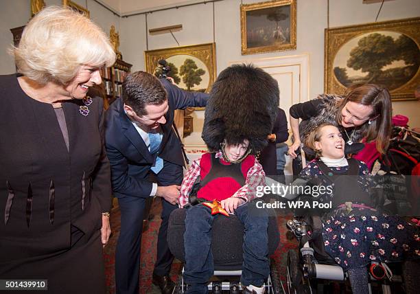 Thomas Melville-Ross 12 trys on a Guards bearskin hat with his sister Alice 12 with Camilla, Duchess of Cornwall, patron of the Helen & Douglas House...