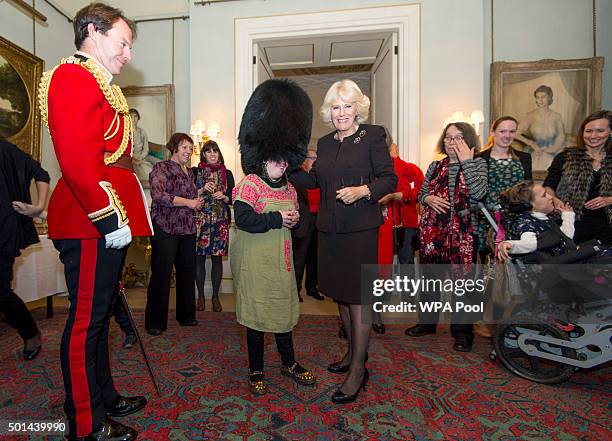 Alice Leigh trys on the bearskin of Captain Matt Wright of the Welsh Guards as Camilla, Duchess of Cornwall, patron of the Helen & Douglas House and...