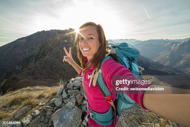 young woman hiking reaches mountain top and takes selfie - rock climbing stock pictures, royalty-free photos & images