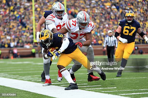 Quarterback John O'Korn of the Michigan Wolverines is pushed out of bounds by linebacker Joshua Perry of the Ohio State Buckeyes during the game at...