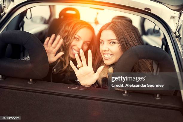 two female friends waving goodbye from back seat - goodbye single word stock pictures, royalty-free photos & images