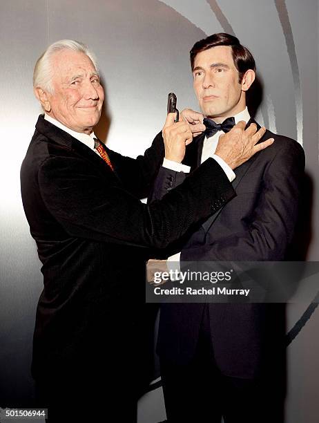 Actor George Lazenby poses with his wax figure during the Madame Tussauds Hollywood reveal of all six James Bonds in wax with special guest George...