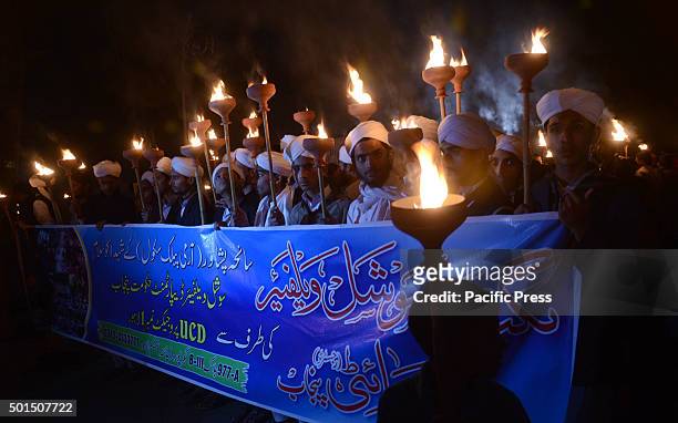 Pakistani students,teachers and civil society activists hold burning torches during a vigil to pay tribute to the victims of the Peshawar school...