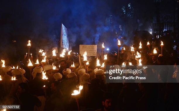 Pakistani students,teachers and civil society activists hold burning torches during a vigil to pay tribute to the victims of the Peshawar school...