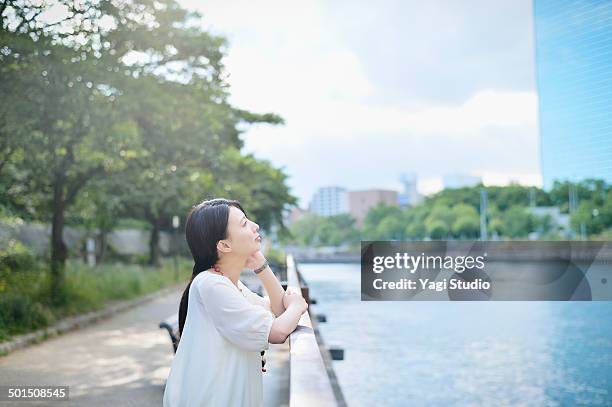 woman standing in park along the river - kin in de hand stockfoto's en -beelden