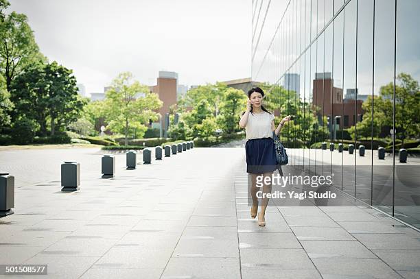woman walking in front of office building - japanese short skirts stockfoto's en -beelden