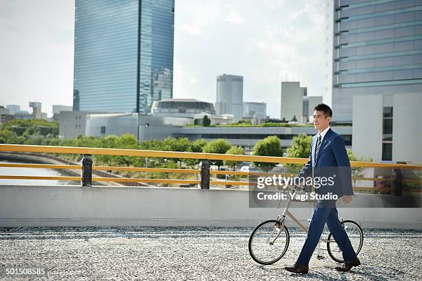 businessman riding bicycle on bridge - bridge side view stock pictures, royalty-free photos & images