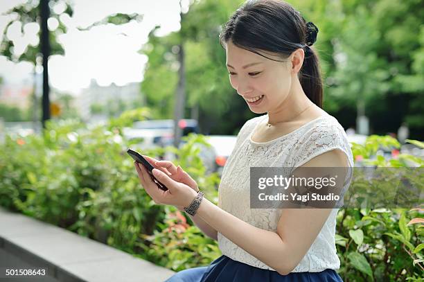 woman using smartphone in urban park - japanese brush stroke stock pictures, royalty-free photos & images