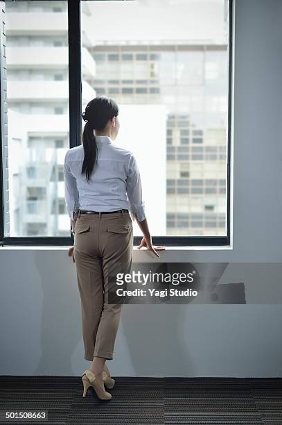 businesswoman looking out window - business women pants stock-fotos und bilder