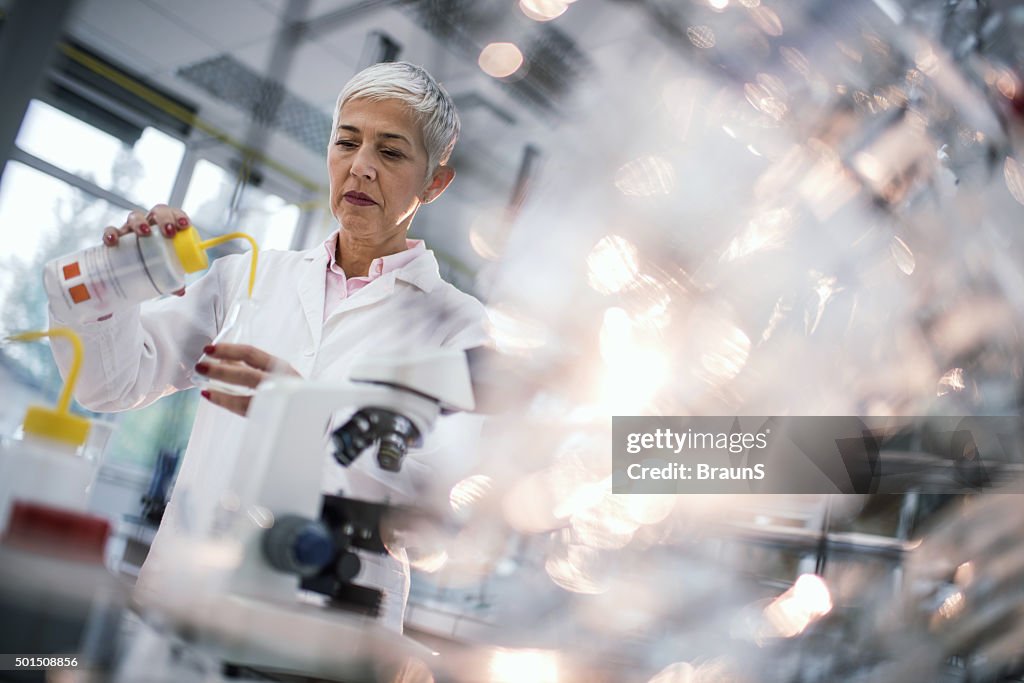 Weibliche kriminaltechnische Wissenschaftler arbeiten mit Chemikalien in Labor.