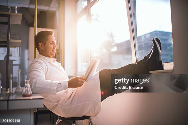 happy male scientist reading scientific data in a laboratory. - doctor publication stock pictures, royalty-free photos & images