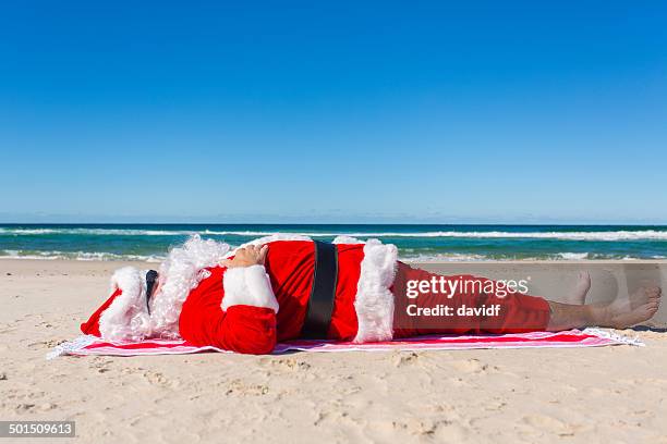 santa sunbaking on the beach - santa claus lying stockfoto's en -beelden