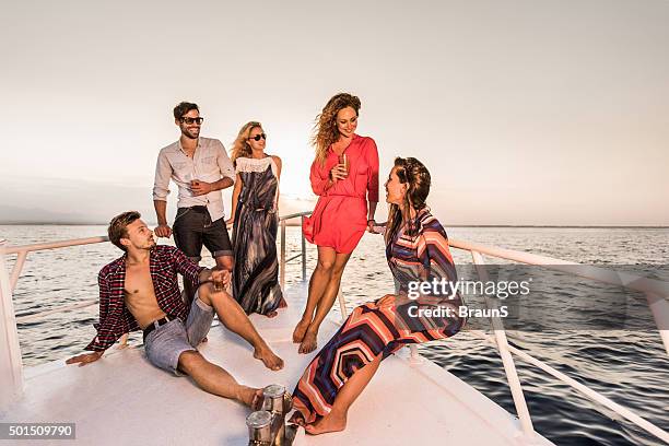 young happy friends relaxing on a yacht and communicating. - yacht party stock pictures, royalty-free photos & images