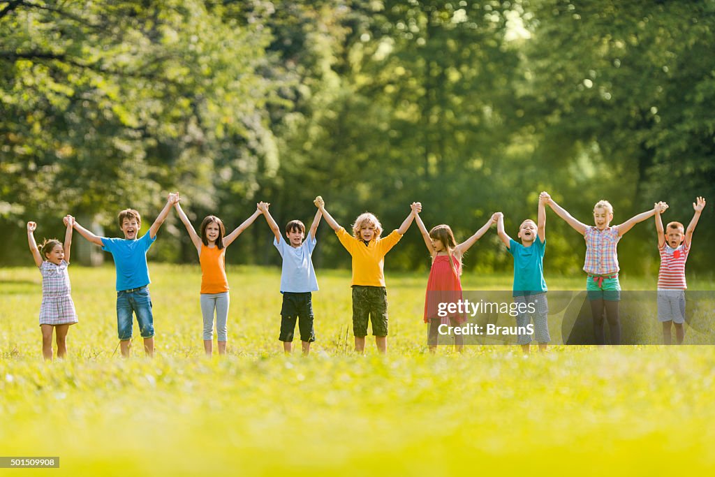 Large group of carefree children holding hands in the park.