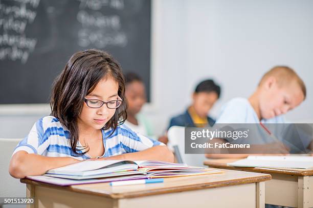 reading a textbook in class - kids reading glasses stock pictures, royalty-free photos & images