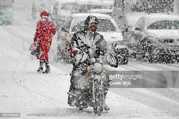 Man rides on a motorbike in snow on December 16, 2015 in Yantai, Shandong Province of China. Yantai Weather Bureau has issued yellow alert to ice...