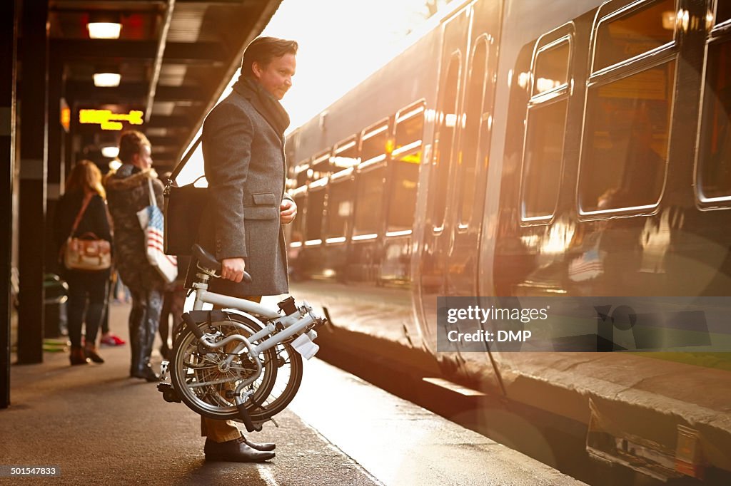 Businessman with folding cycle boarding train