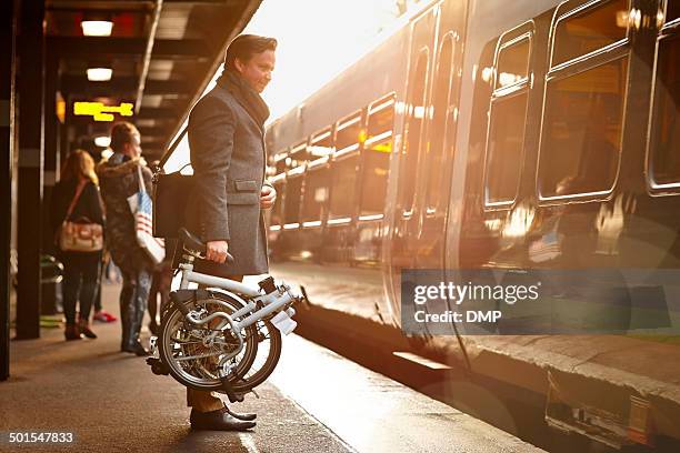 businessman with folding cycle boarding train - urban bicycle stock pictures, royalty-free photos & images