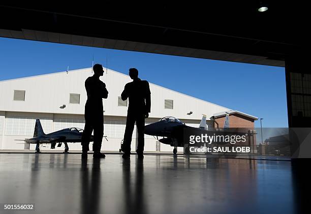 Pilots with the US Air Force stand inside a hangar alongside a F-15 fighter jet and a T-38 Talon trainer jet during the inaugural Trilateral Exercise...