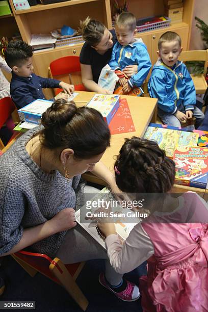 Immigrant mothers with their children look through games and books during the presentation of a new initiative to help children of refugees learn to...
