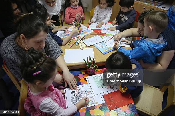 Immigrant mothers with their children look through games and books during the presentation of a new initiative to help children of refugees learn to...