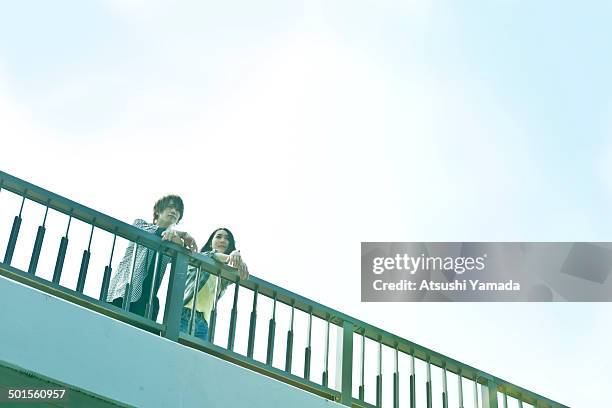 young couple talking on footbridge - passerelle pont photos et images de collection
